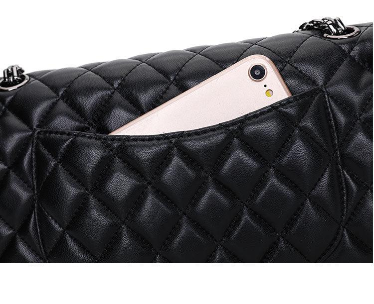 Black quilted genuine leather shoulder bag with exterior pocket holding a smartphone