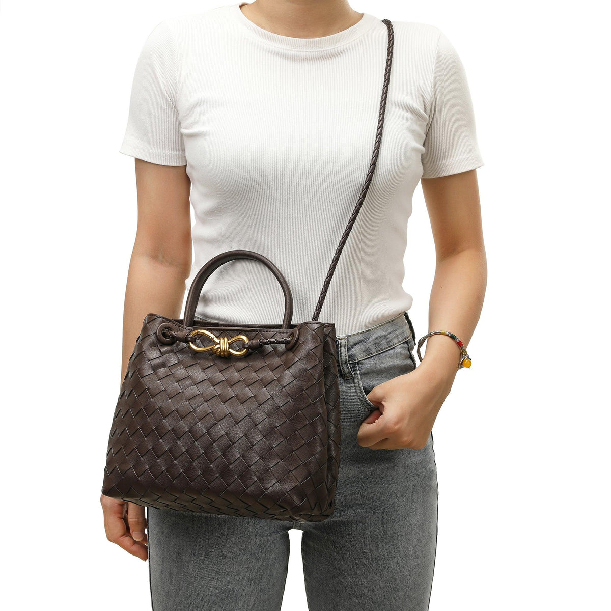 Woman carrying a dark brown woven leather shoulder bag with gold metal buckle detail