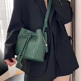 Woman wearing black blazer with green woven lambskin leather bucket bag, crossbody style