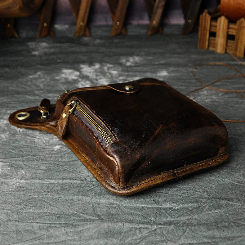 Full grain dark brown leather leg bag with zipper pockets and metal rivet details