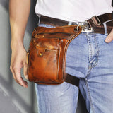 Brown full grain leather leg bag with multiple pockets worn on waist and thigh, motorcycle style.