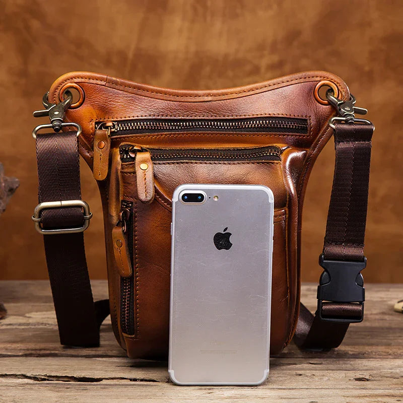 Full grain leather leg bag with adjustable straps, multiple zipped pockets, and phone for scale