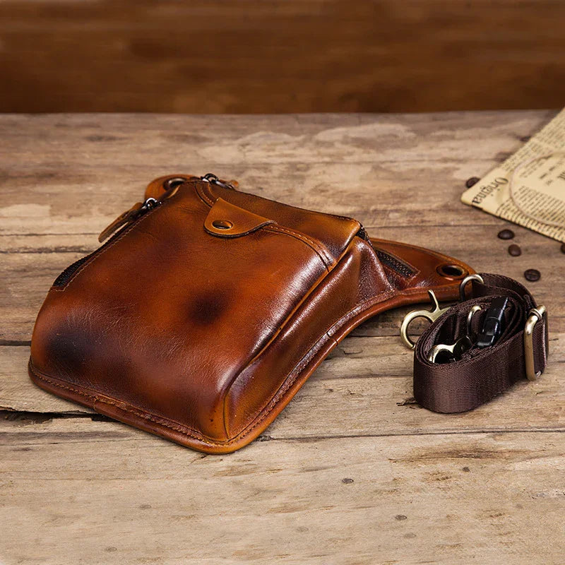 Full grain brown leather leg and waist bag for men, rustic style on wooden surface