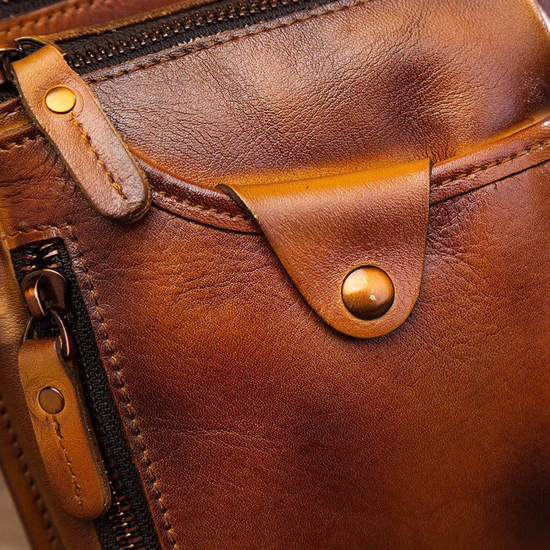 Close-up of brown full grain leather leg bag with zippers, pockets, and brass button detail