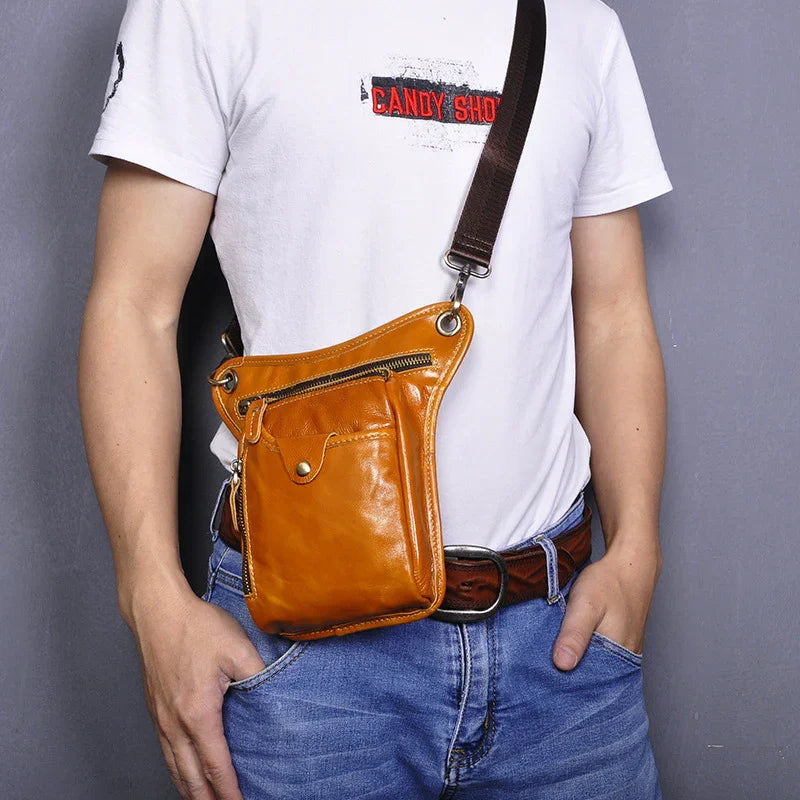 Brown full-grain leather leg bag with zip pocket and adjustable strap worn by man in jeans.