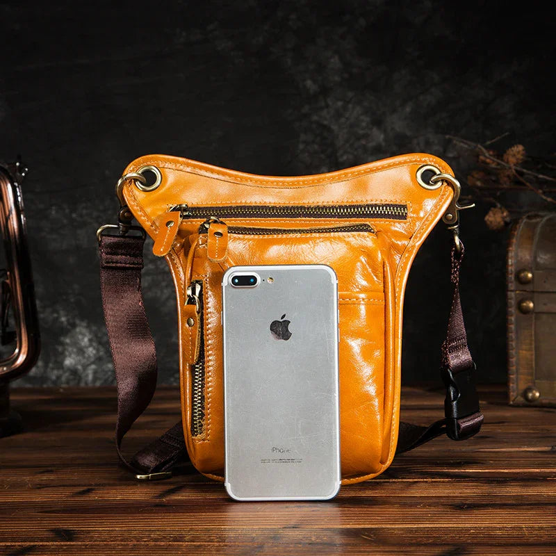 Full grain leather leg bag with brown straps, multiple zip pockets, and a smartphone for scale