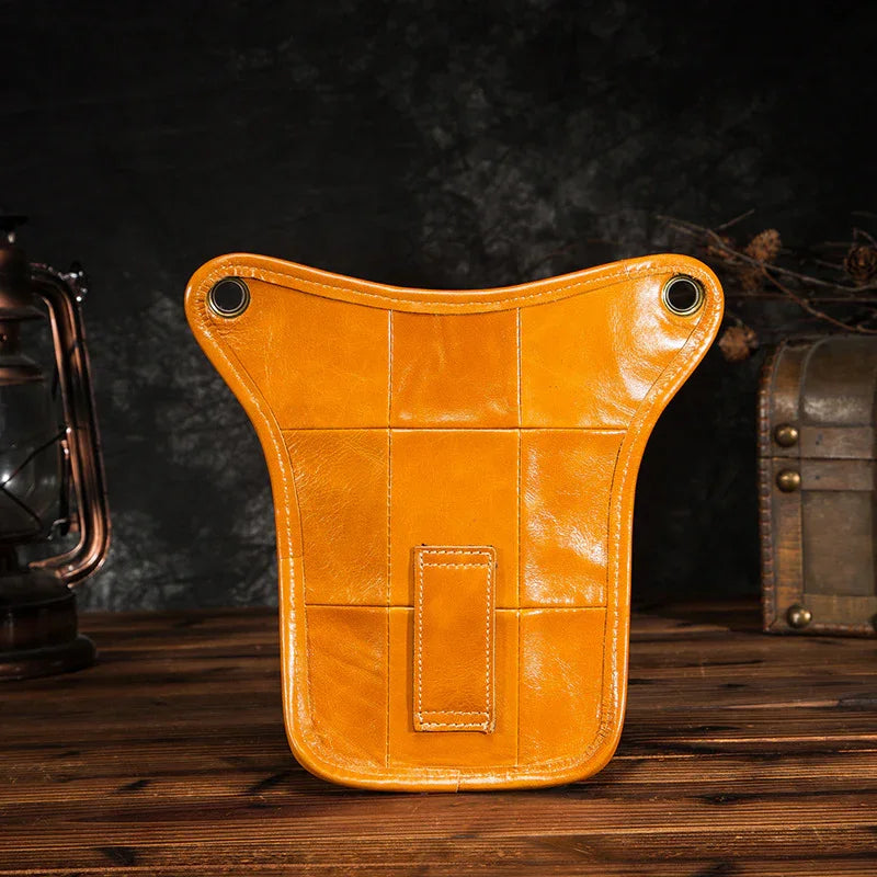 Full grain leather leg bag in tan, vintage style, on rustic wooden table with dark background