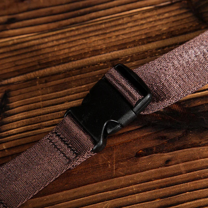 Close-up of brown adjustable nylon strap with black plastic buckle on wooden surface