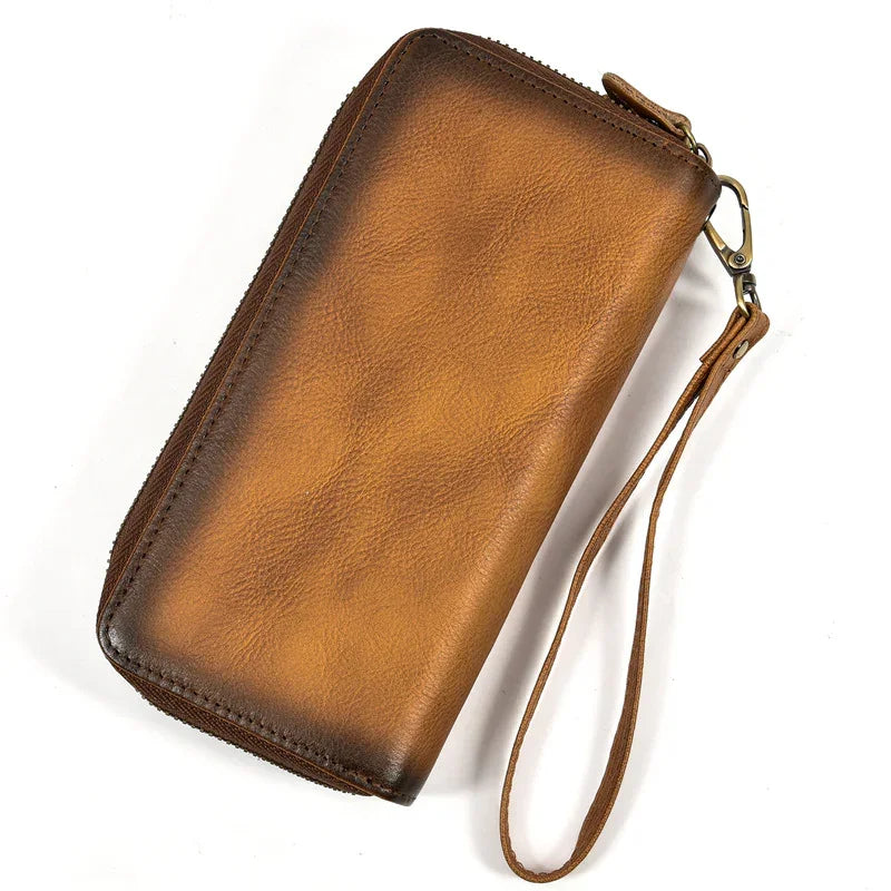 Brown full grain leather long zip wallet with wrist strap on white background