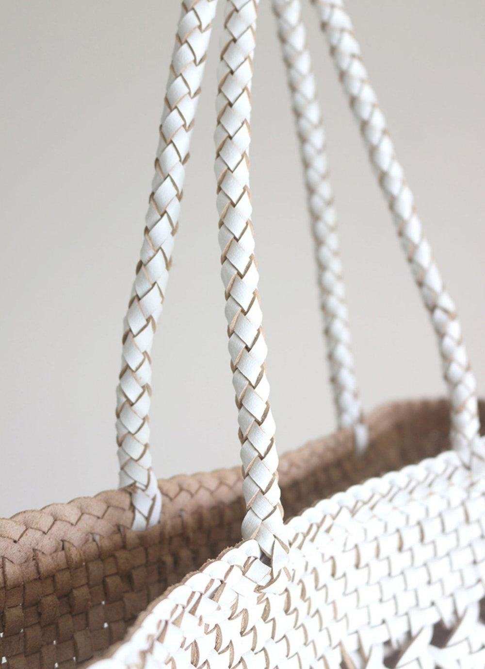 Close-up of hand-woven genuine leather tote bag with braided white handles