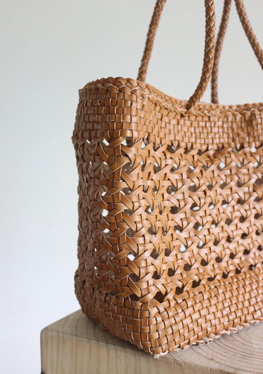 Genuine leather hand-woven tote bag with cuboid shape and braided handles, shown in close-up.