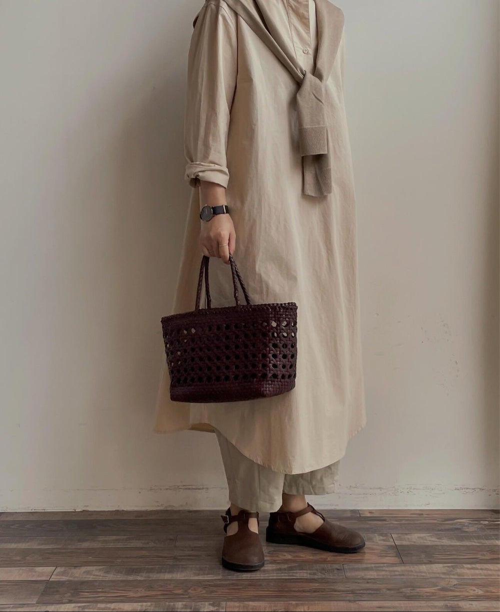 Woman in neutral outfit holding a handwoven genuine leather cuboid tote bag