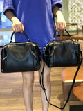 Two black genuine leather handbags in different sizes, shown by a person indoors
