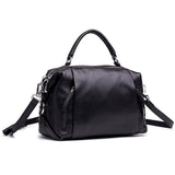 Black genuine leather Boston handbag with top handle and adjustable shoulder strap on white background