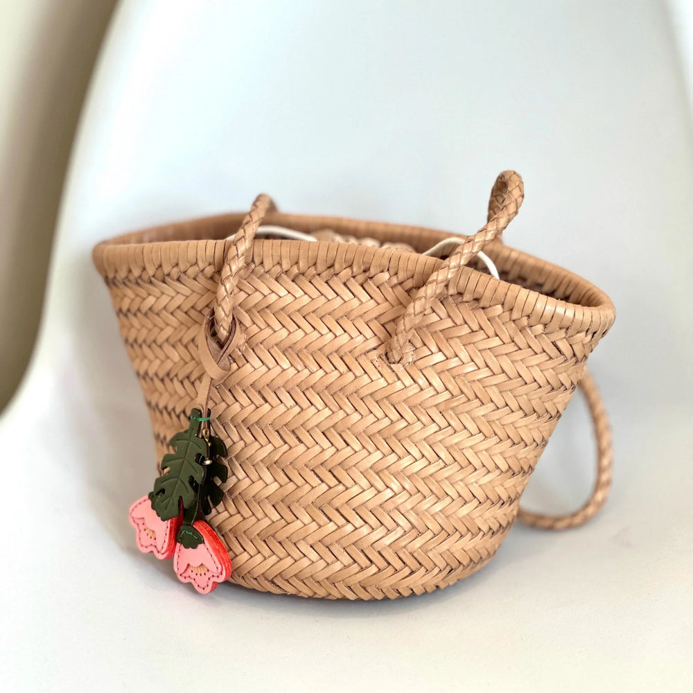 Hand-woven cowhide leather bucket bag with braided drawstring and decorative charms