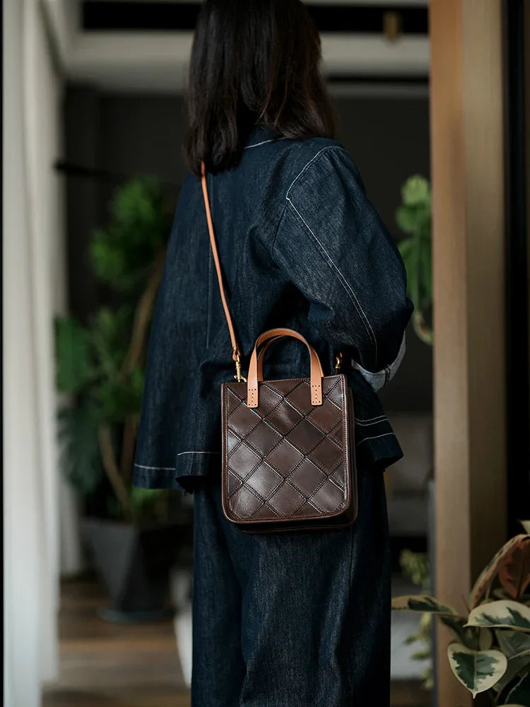 Woman wearing a dark brown woven cowhide leather shoulder bag with tan straps indoors