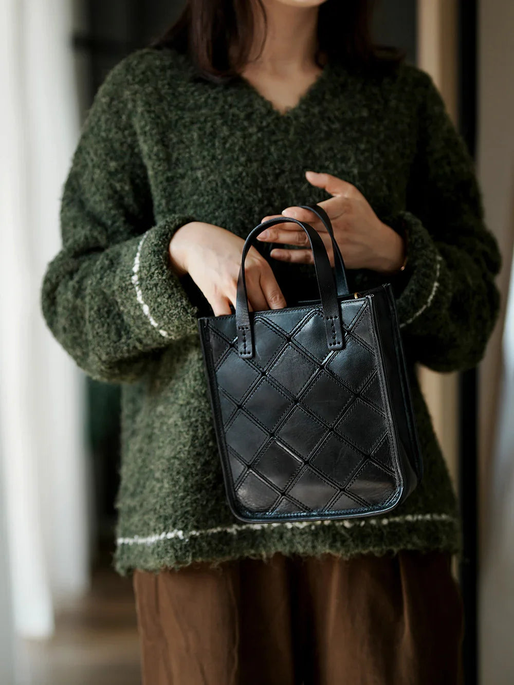 Woman holding black handcrafted cowhide leather handbag with quilted pattern
