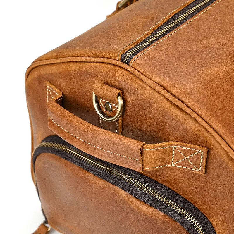 Close-up of a handmade full grain leather duffle bag in brown with zipper pocket and handle
