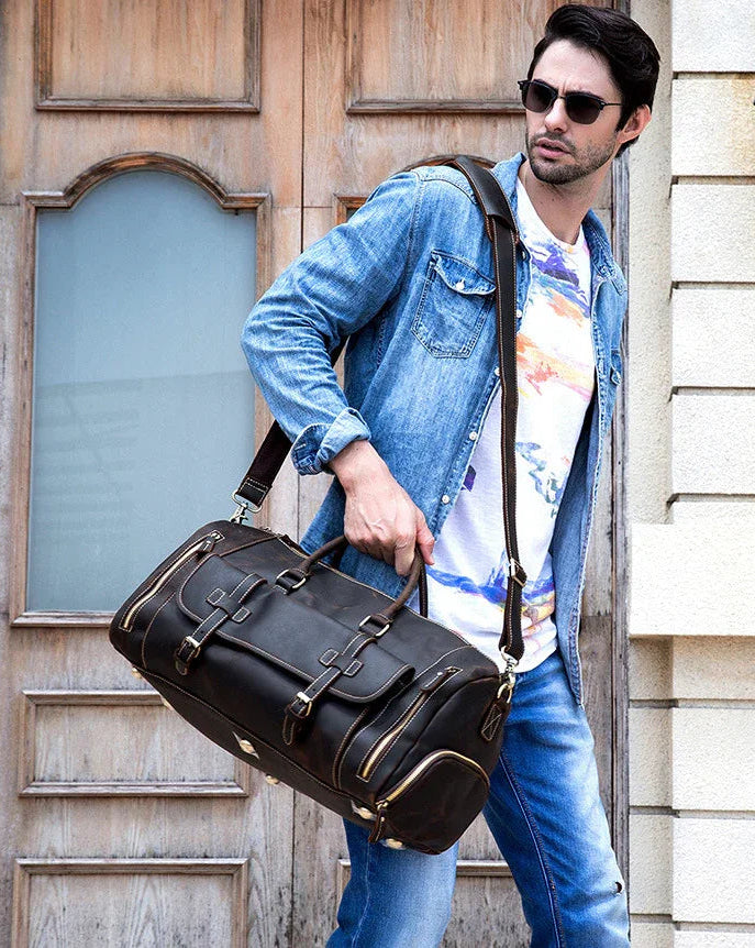 Man in denim jacket carrying large dark brown full grain leather duffle bag with shoe compartment