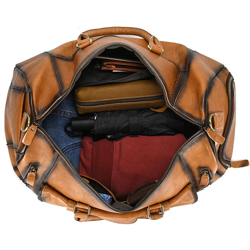 Open full grain leather duffle bag packed with clothes and accessories, travel bag