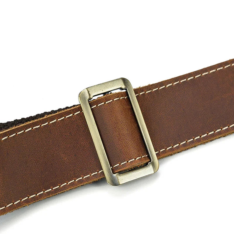 Close-up of a brown full grain leather bag strap with metal buckle and white stitching