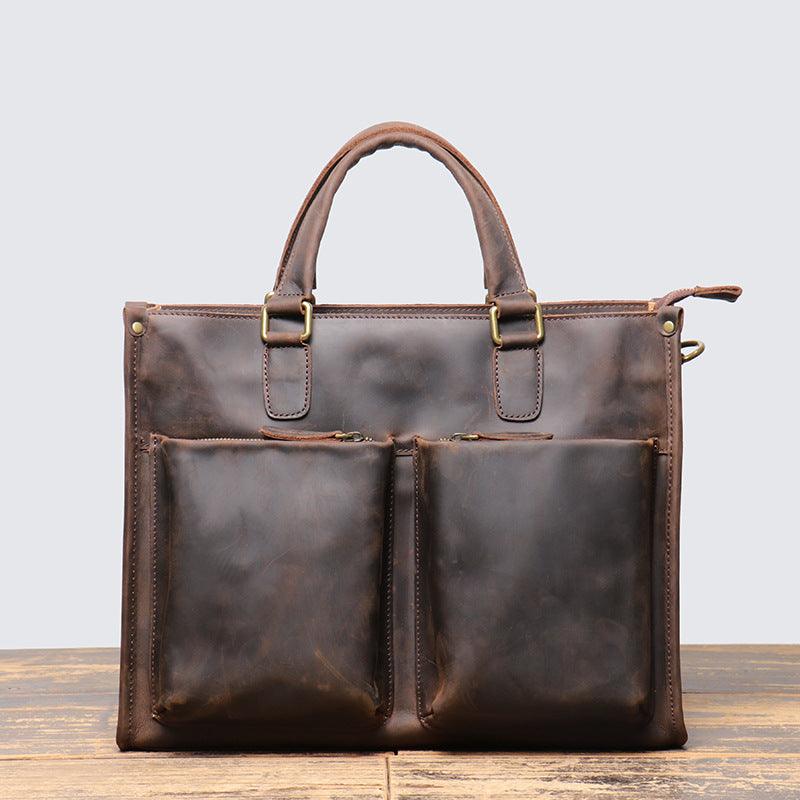 Handmade full grain leather messenger bag with dual front pockets, brown satchel on wood surface.