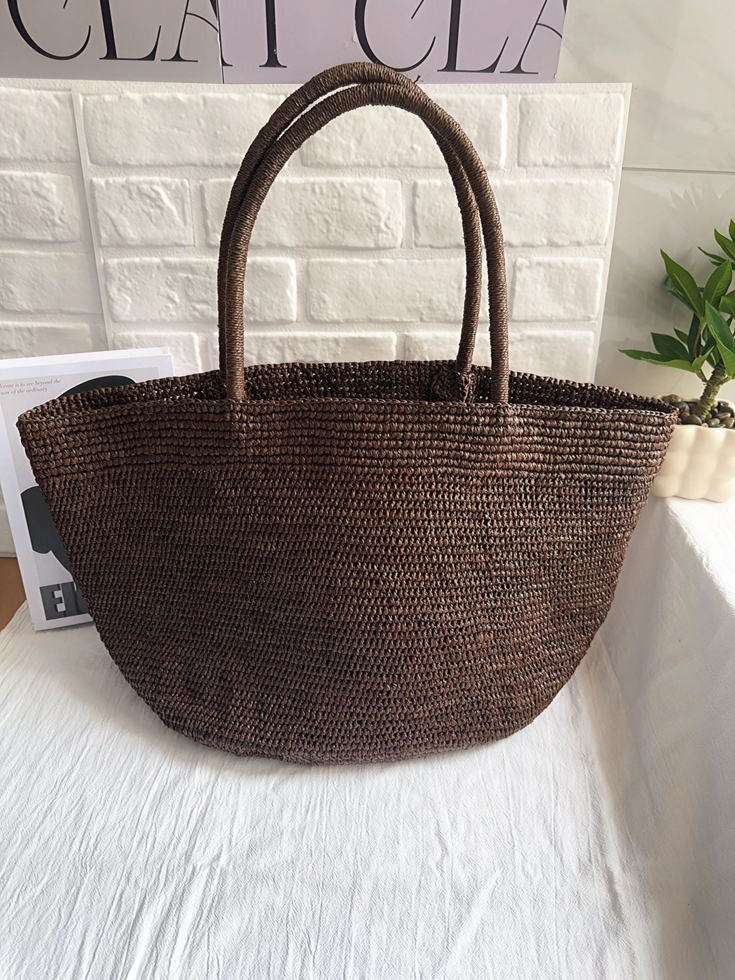 Handwoven raffia straw tote standing upright – structured natural fibre beach bag large size