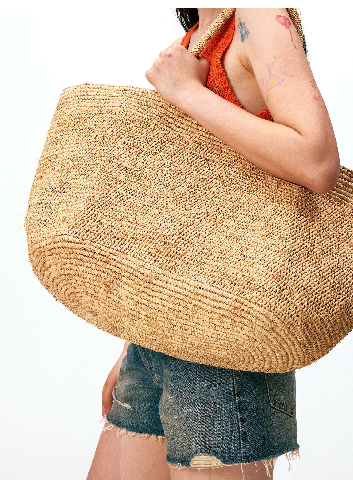 Handwoven raffia tote bag with scarf styling – natural straw beach bag worn with linen dress