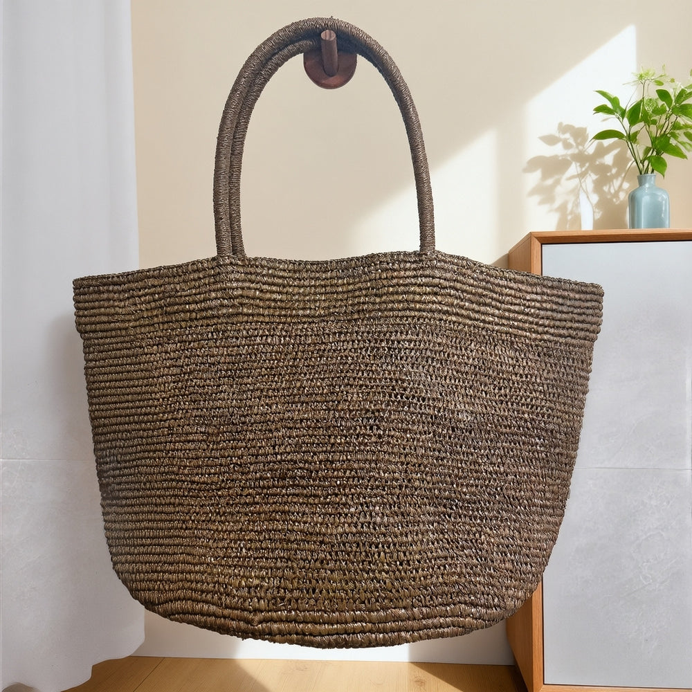 Handwoven raffia tote bag lifestyle – natural straw beach bag worn over shoulder at beach