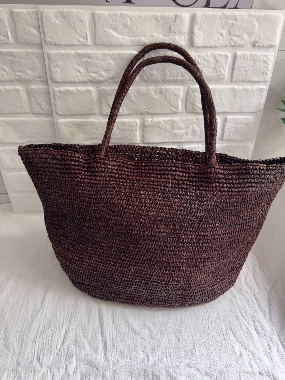 Natural raffia straw tote bag in sunlight – large handwoven beach vacation bag eco-friendly