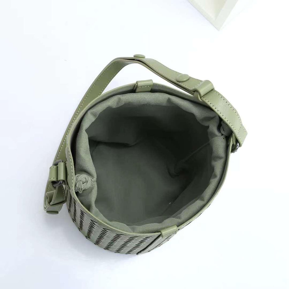 Open green woven leather bucket bag with adjustable shoulder strap on white background