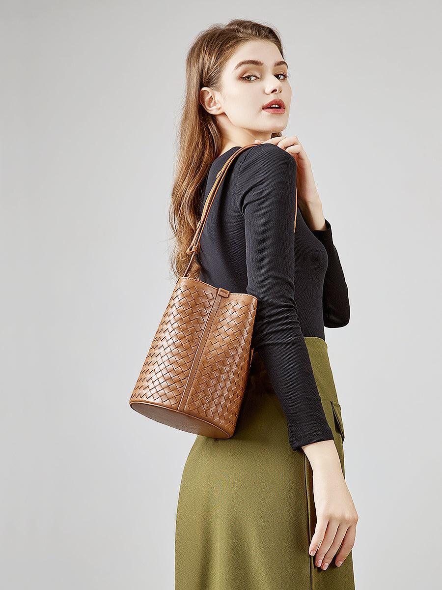 Woman wearing a brown woven lambskin leather bucket bag crossbody style