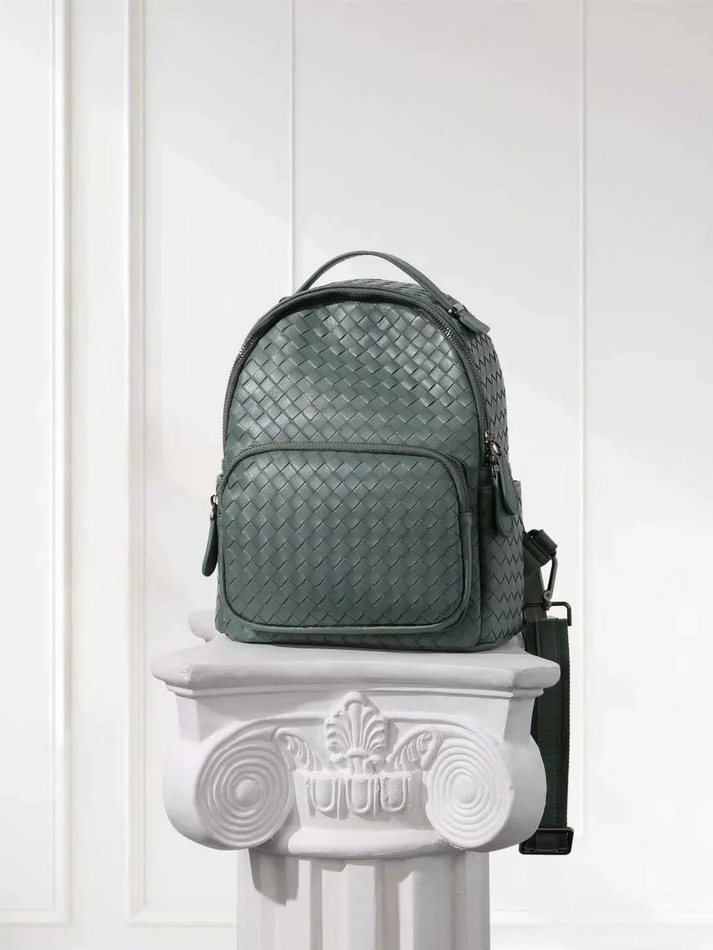 Handwoven green lambskin leather small backpack with quilted texture on a white pedestal