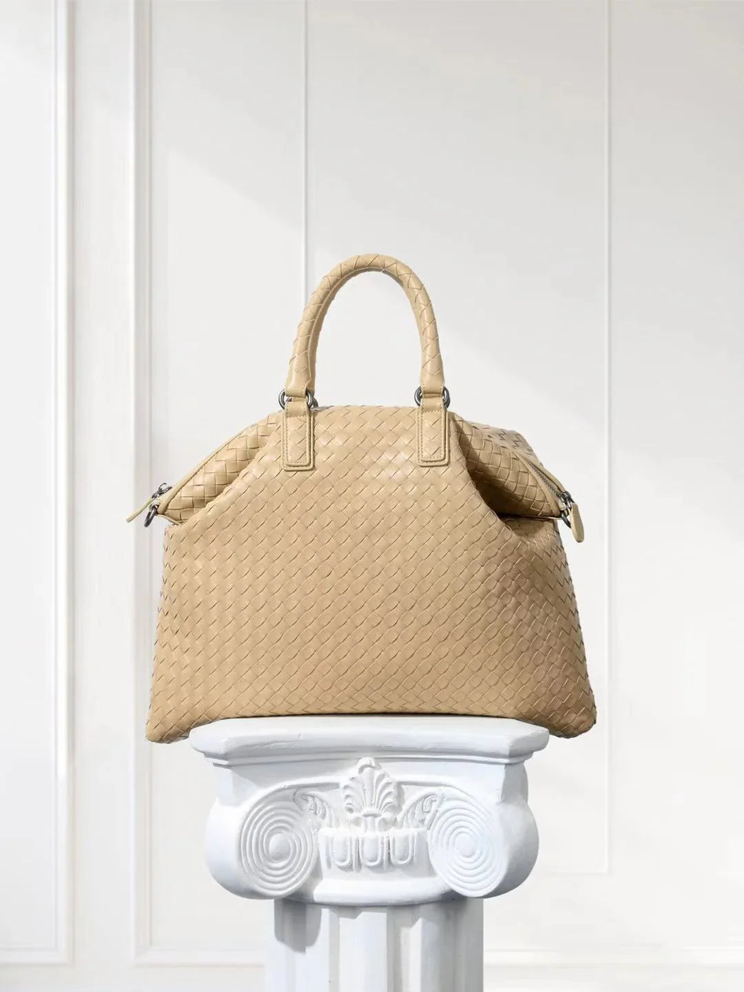 Beige woven lambskin leather tote bag with top handles on a white pedestal
