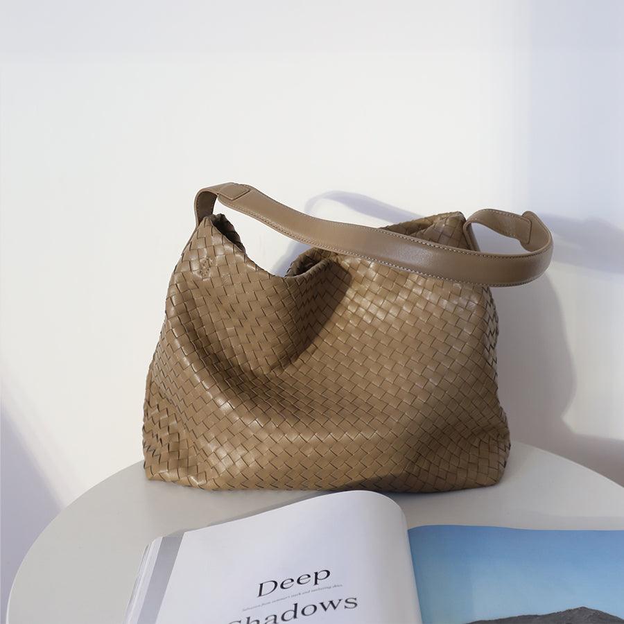 Tan woven lambskin leather tote bag with single shoulder strap on white table