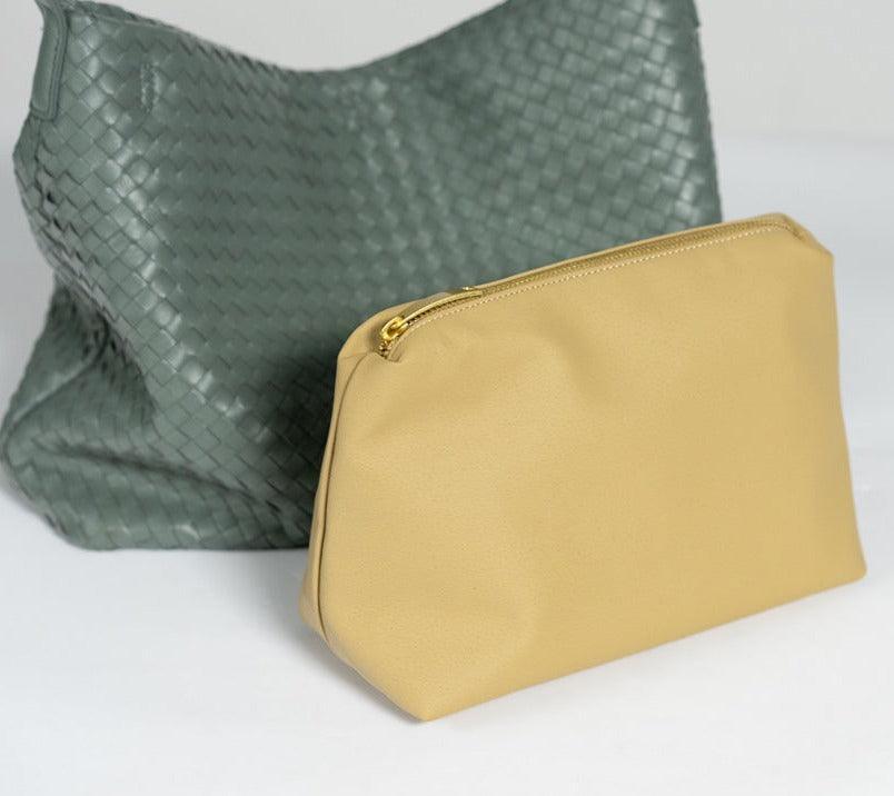 Green woven leather tote bag with matching beige zippered pouch on white surface