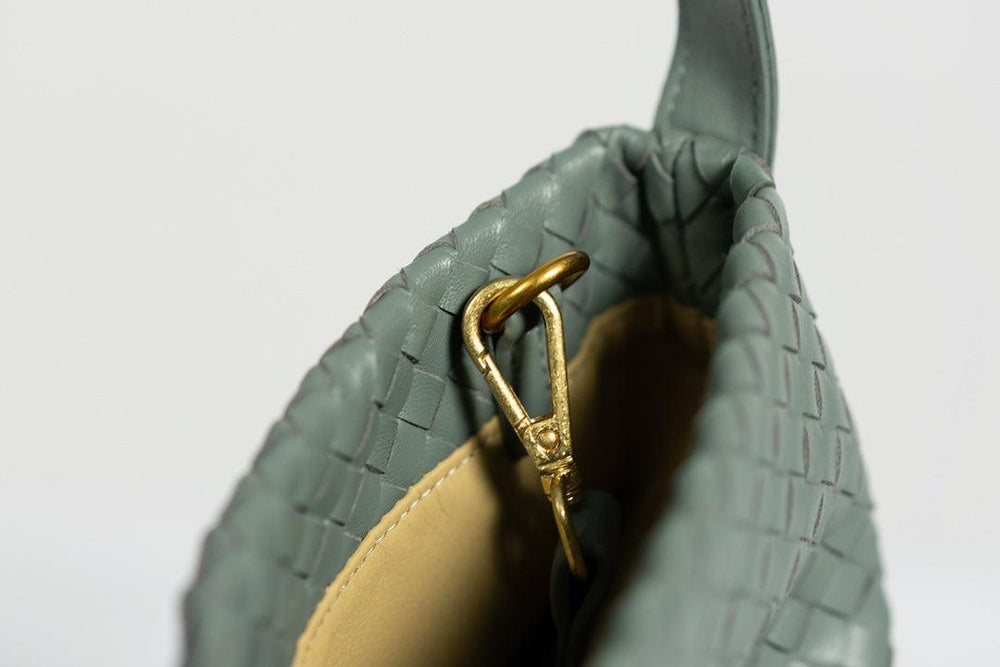 Close-up of green woven lambskin leather tote bag with gold clasp and tan interior.