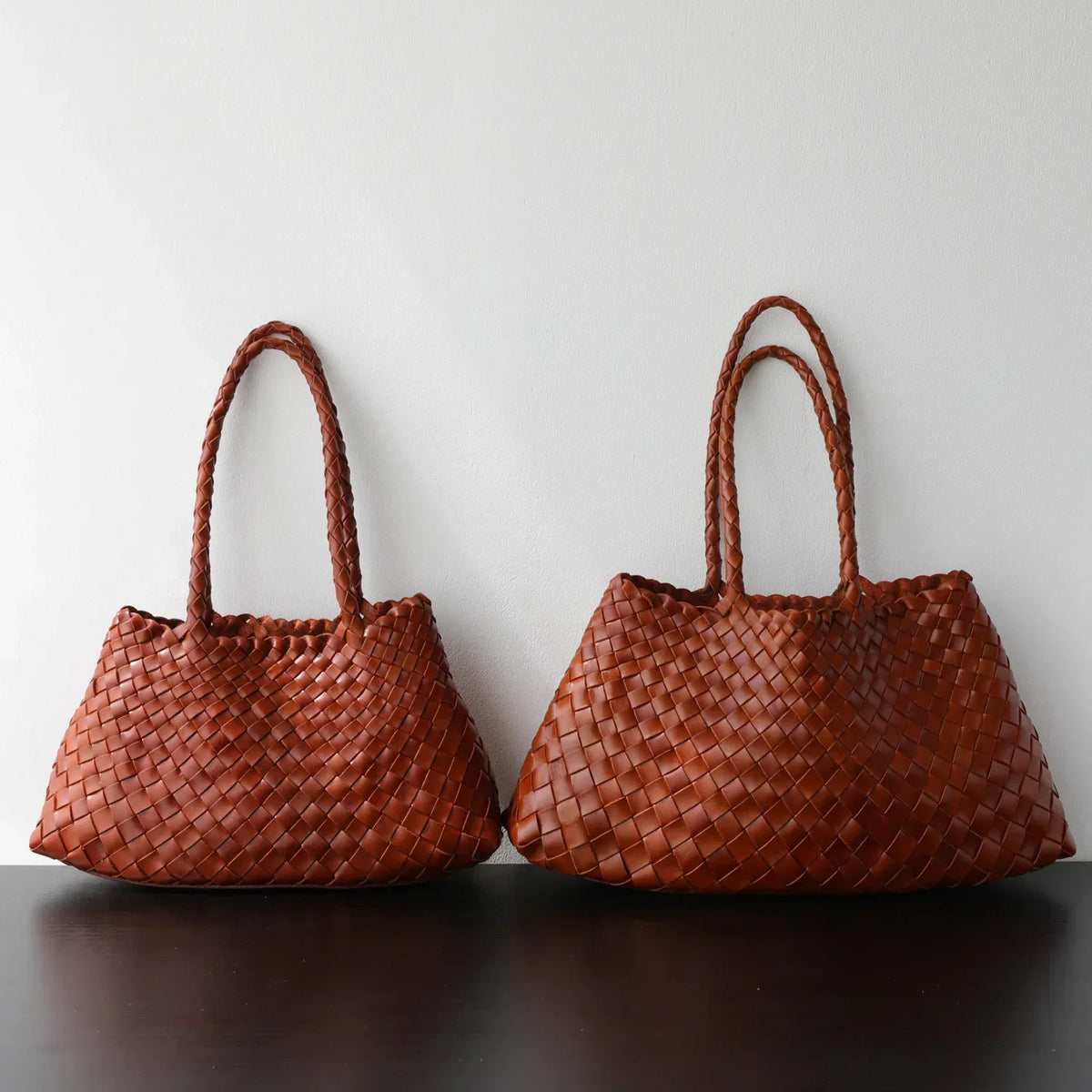 Woman carrying a dark brown woven leather hobo bag with trapezoidal shape Tan Brown