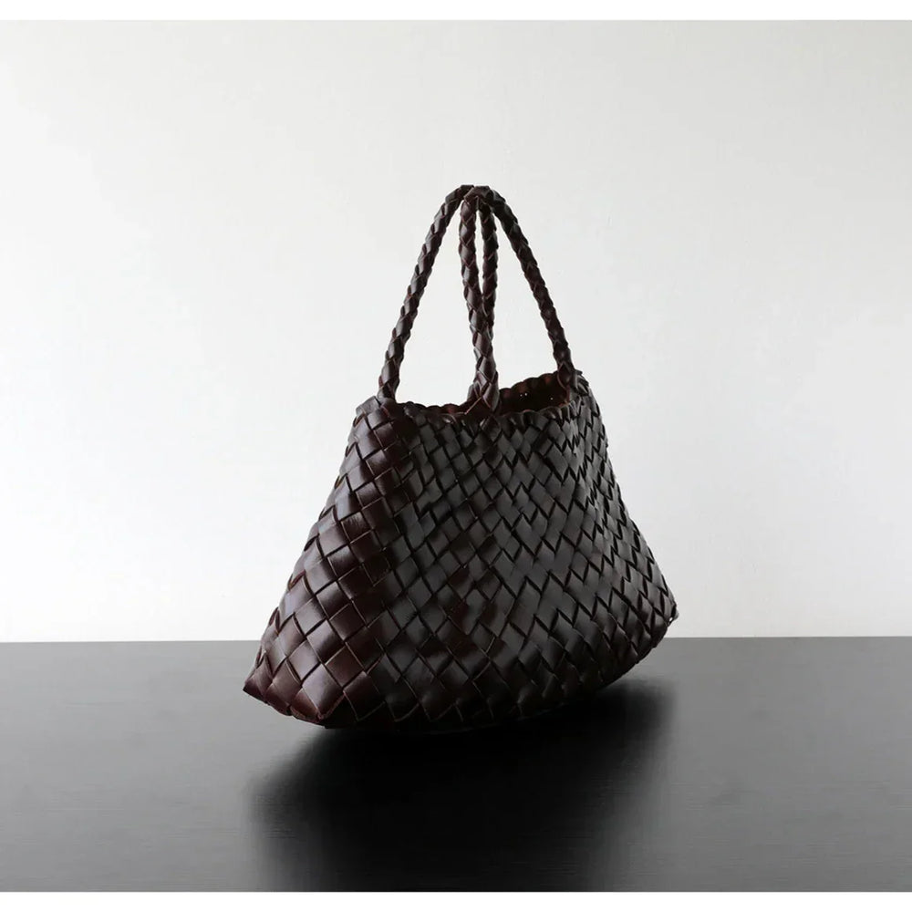 Brown woven leather hobo shoulder bag with braided handles on a black table