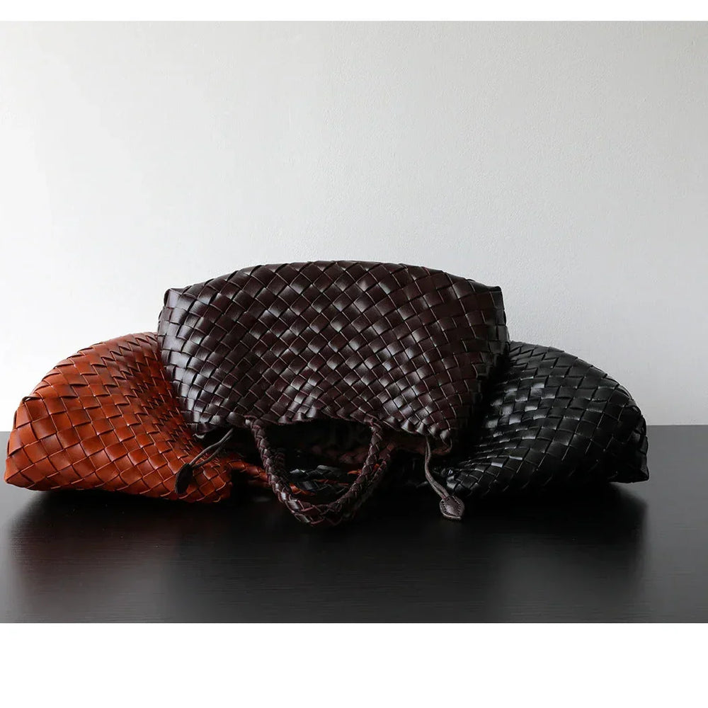 Three woven leather hobo bags in brown, black, and tan on a dark surface