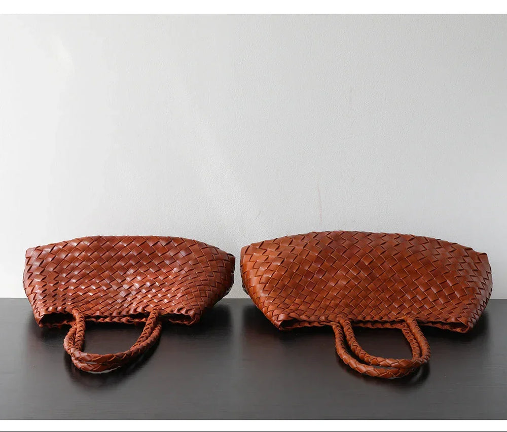 Two brown woven leather hobo shoulder bags with braided handles on a black surface