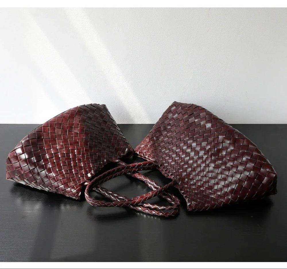 Handcrafted brown woven leather hobo bags with long handles on a dark surface