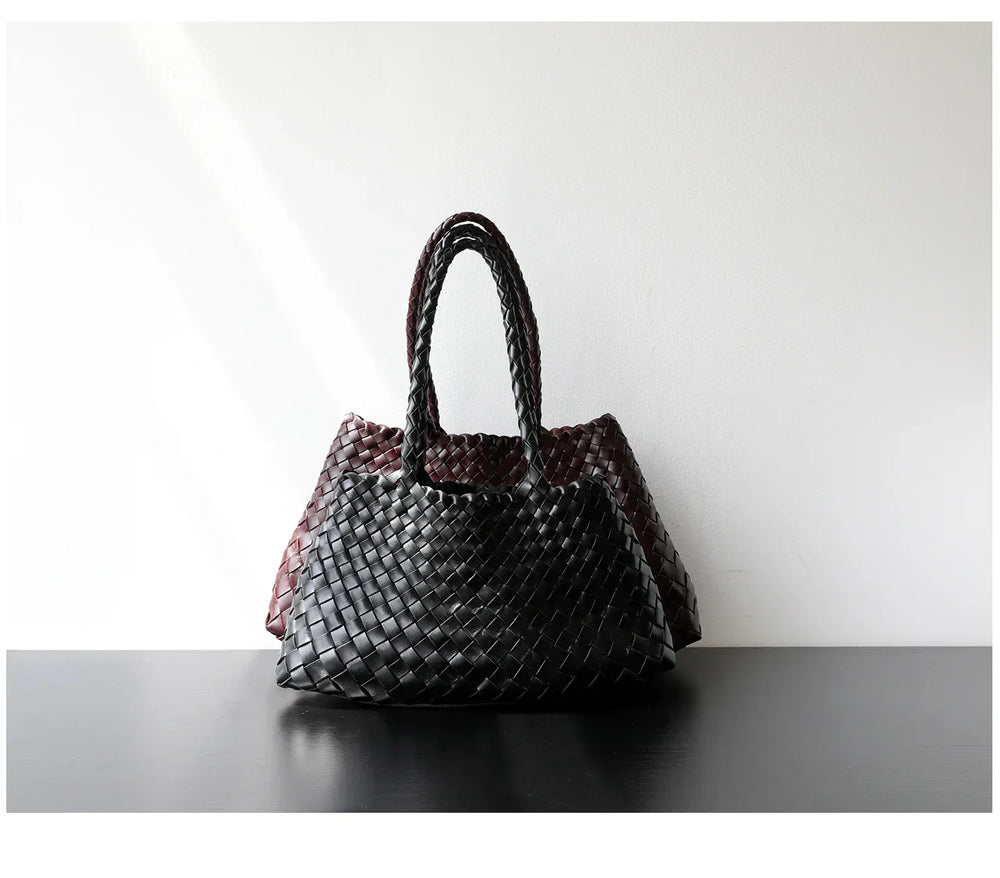Handcrafted black and brown woven leather shoulder bags with long handles on a table
