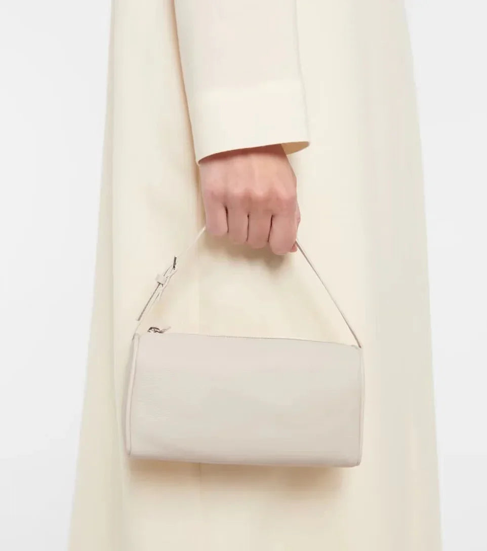 Mini beige lambskin leather Boston bag with top handle, held by person in cream coat