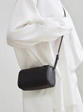 Minimalist black leather mini box bag with crossbody strap, worn over a white shirt