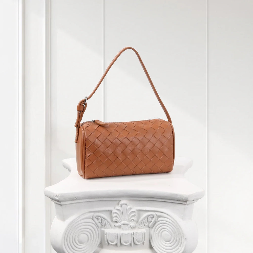 Tan woven lambskin leather mini handbag with short strap, displayed on white pedestal