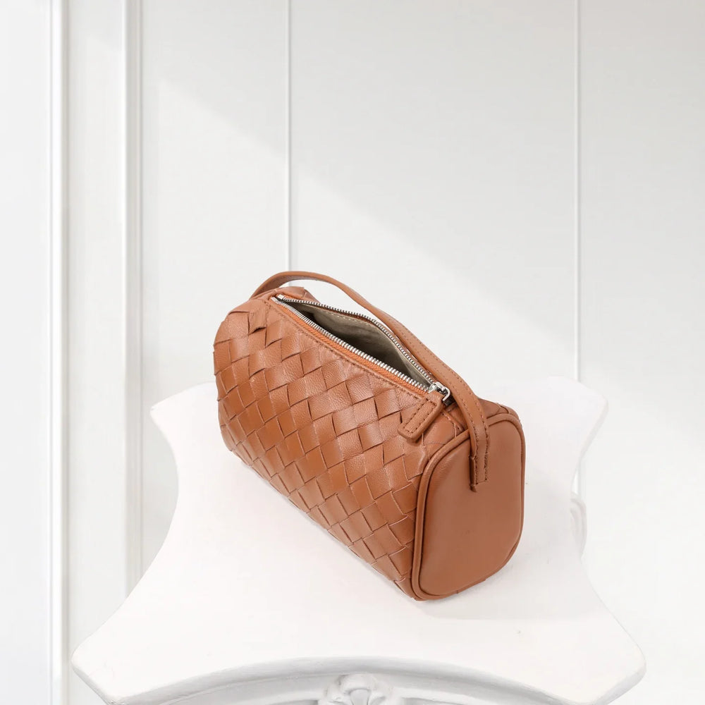 Tan lambskin woven leather mini Boston bag with zipper, displayed on white table