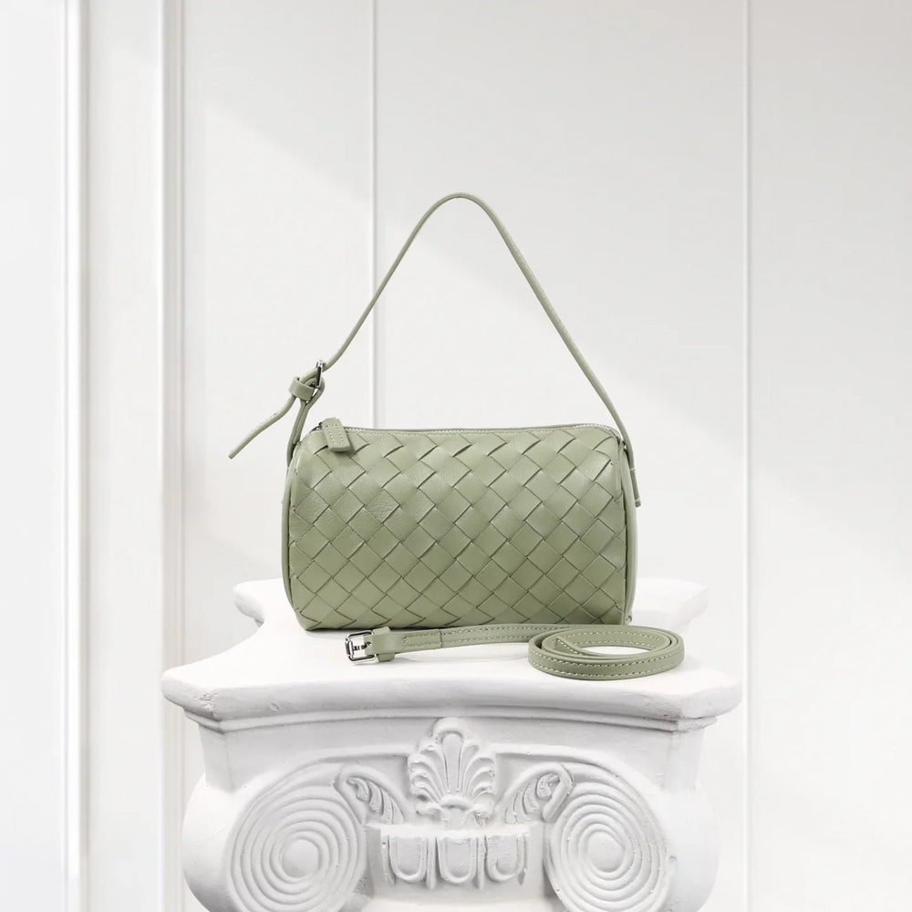 Light green woven lambskin leather mini Boston bag with detachable strap on white pedestal