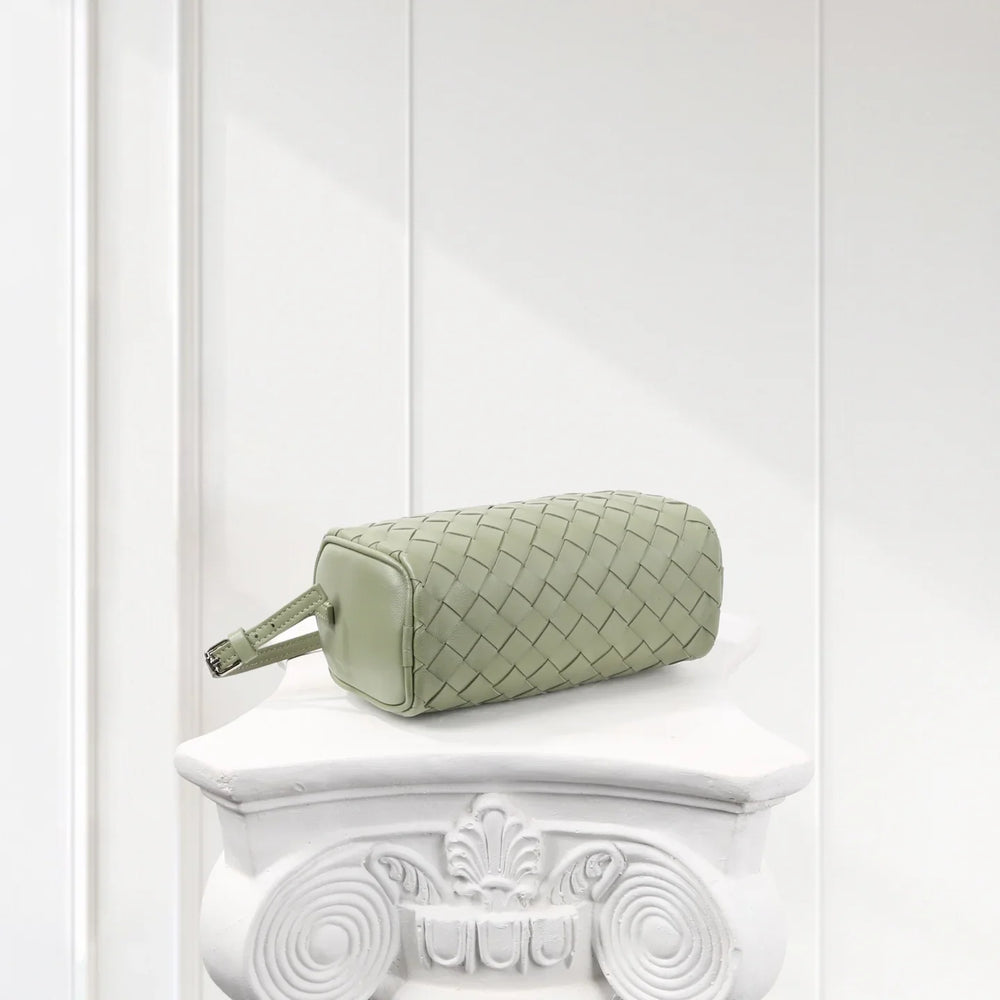 Sage green woven lambskin leather mini Boston bag with shoulder strap on a white pedestal