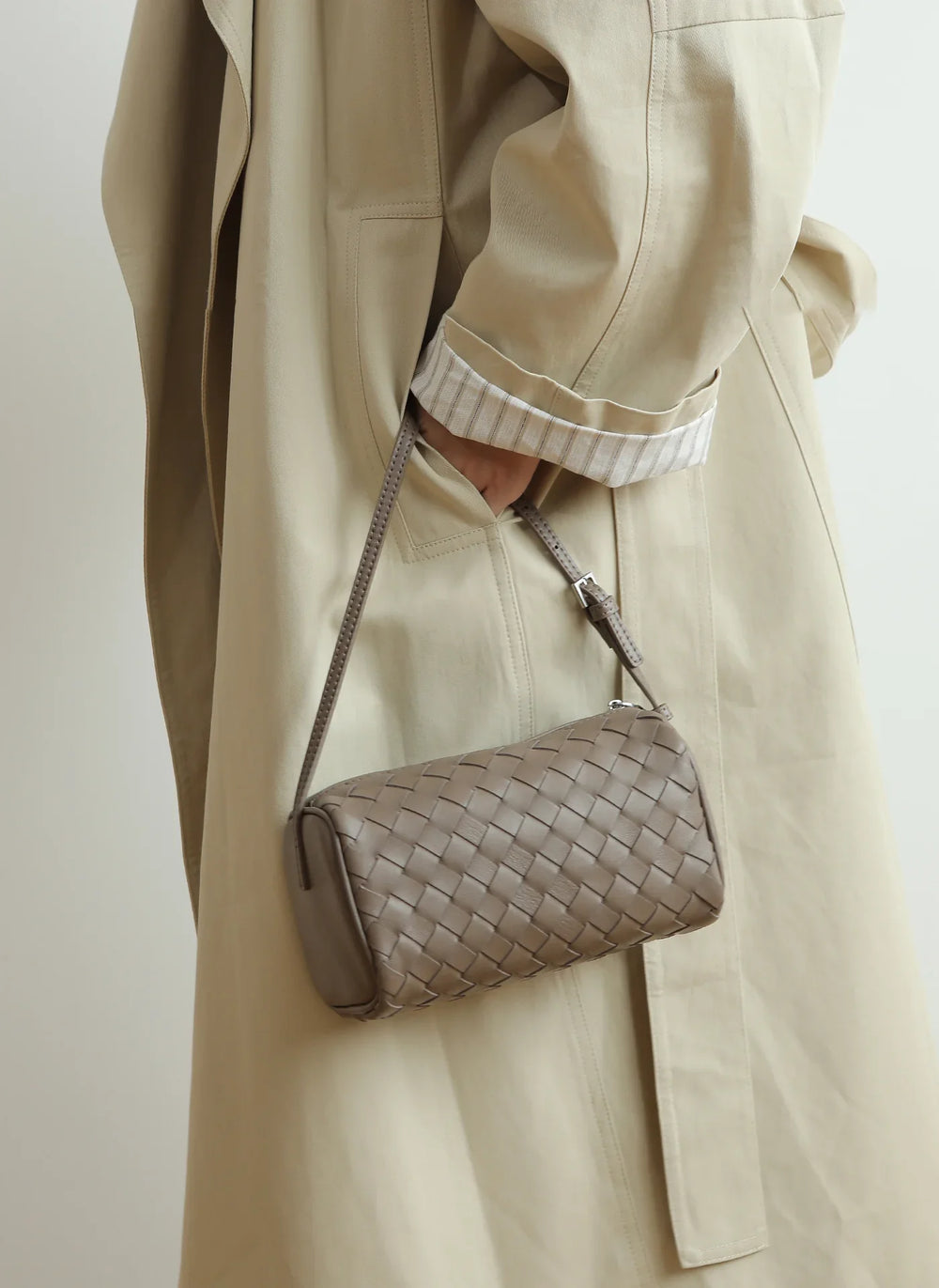 Mini woven lambskin leather crossbody bag with adjustable strap, styled on a neutral trench coat.